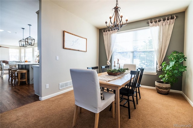 carpeted dining space with an inviting chandelier