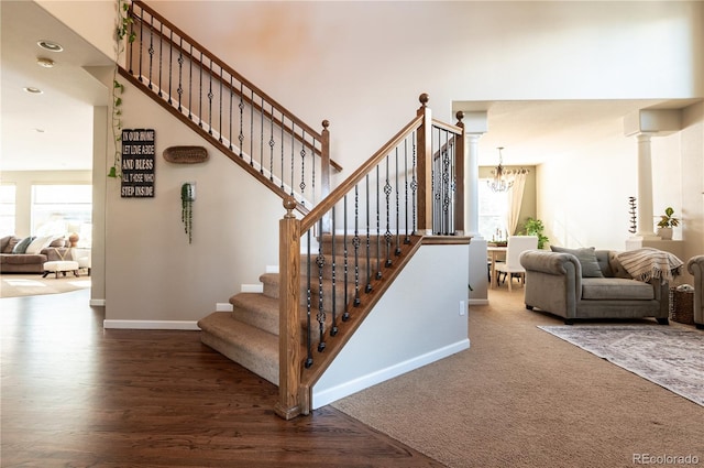 staircase with ornate columns, carpet flooring, and a chandelier