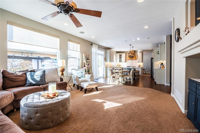 living room with ceiling fan and dark colored carpet