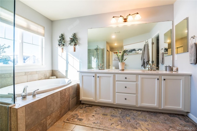 bathroom with tile patterned flooring, vanity, and tiled bath