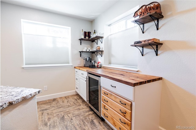 kitchen featuring white cabinets, wine cooler, and butcher block countertops