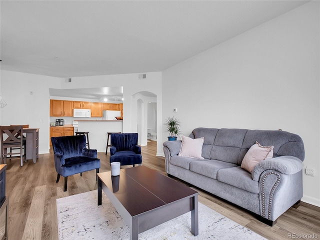 5765 N Genoa Way Unit 1-103, Aurora, CO 80019 - living room featuring arched walkways, light wood-style floors, and baseboards