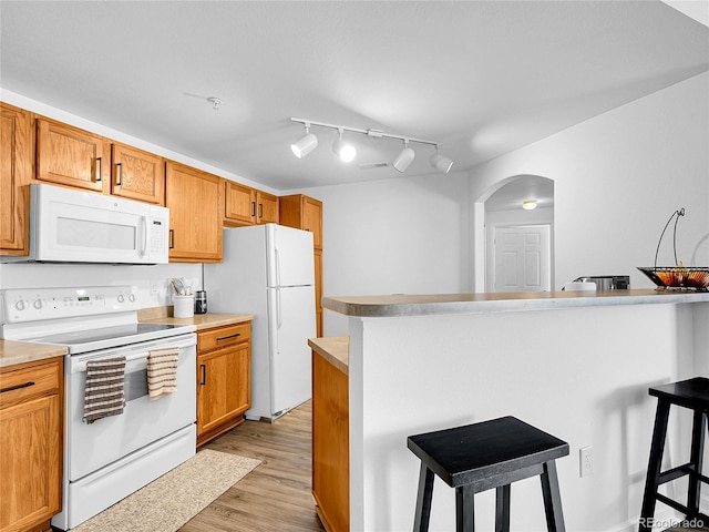 5765 N Genoa Way Unit 1-103, Aurora, CO 80019 - kitchen with white appliances, a kitchen breakfast bar, arched walkways, and light wood-style floors
