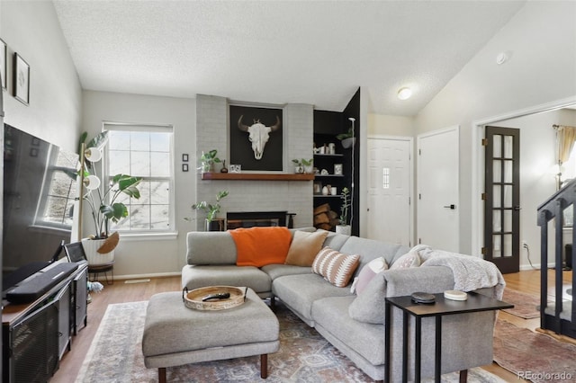 8220 W 90th Pl Unit 2003, Broomfield, CO 80021 - living room with a brick fireplace, vaulted ceiling, wood finished floors, a textured ceiling, and baseboards