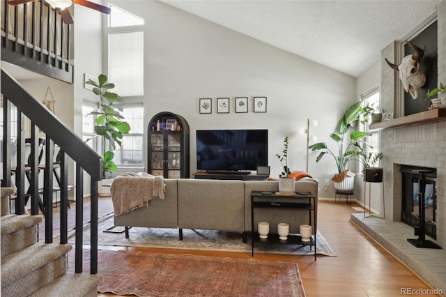 8220 W 90th Pl Unit 2003, Broomfield, CO 80021 - living area featuring wood finished floors, stairway, a brick fireplace, ceiling fan, and high vaulted ceiling