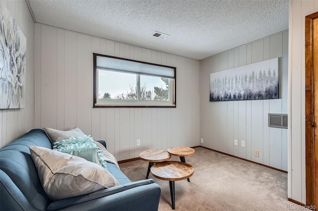 sitting room with wooden walls, carpet floors, and a textured ceiling