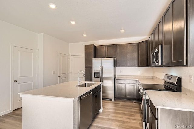 kitchen featuring stainless steel appliances, light hardwood / wood-style flooring, a center island with sink, and sink