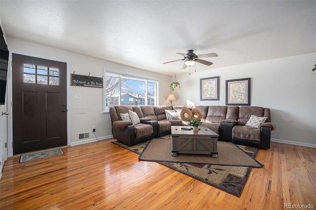 living room featuring a textured ceiling, ceiling fan, and light hardwood / wood-style flooring