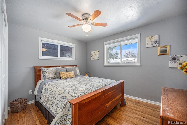 bedroom featuring ceiling fan, light hardwood / wood-style flooring, and a textured ceiling