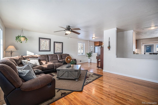 living room with ceiling fan, light hardwood / wood-style flooring, and a textured ceiling