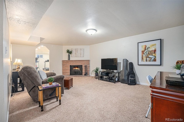 living room with a brick fireplace, carpet floors, and a textured ceiling