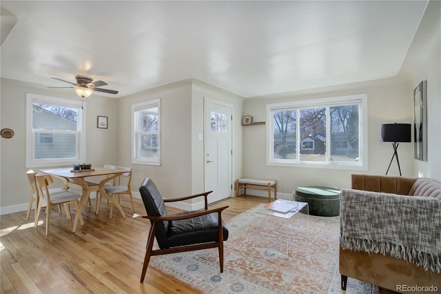 living area featuring baseboards, light wood-style floors, and a ceiling fan