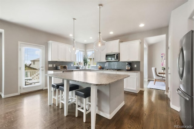 9135 Argentine Pass Trl, Colorado Springs, CO 80924 - kitchen with stainless steel appliances, tasteful backsplash, light countertops, a center island, and dark wood-type flooring
