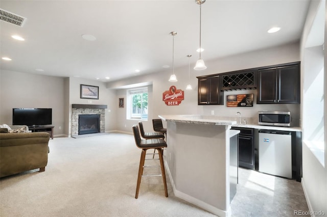 9135 Argentine Pass Trl, Colorado Springs, CO 80924 - kitchen featuring appliances with stainless steel finishes, a kitchen breakfast bar, hanging light fixtures, a stone fireplace, and open floor plan