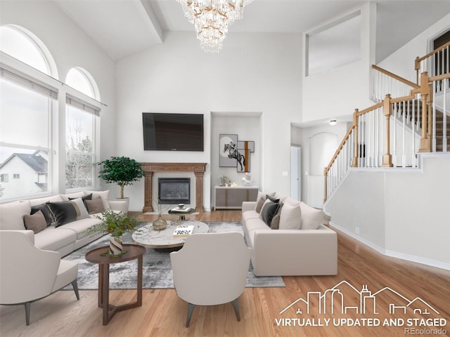 living area with wood finished floors, an inviting chandelier, high vaulted ceiling, and stairway