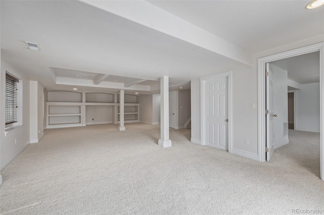 finished below grade area featuring visible vents, baseboards, built in shelves, carpet, and stairs