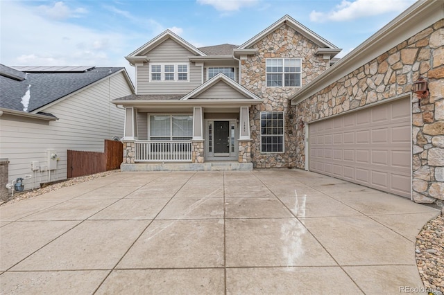 craftsman-style house featuring driveway, stone siding, an attached garage, and covered porch
