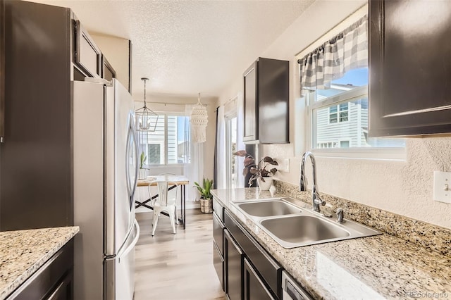 442 Stardust Ct, Dacono, CO 80514 - kitchen featuring decorative light fixtures, a sink, light wood-type flooring, freestanding refrigerator, and a textured ceiling