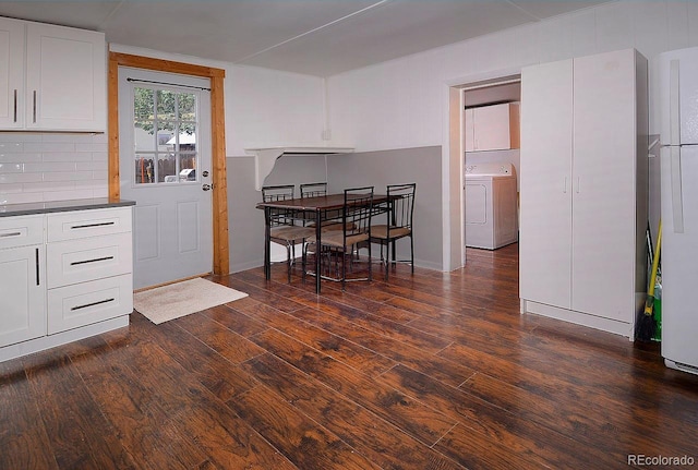 kitchen with washer / clothes dryer, dark wood-type flooring, backsplash, and white cabinetry