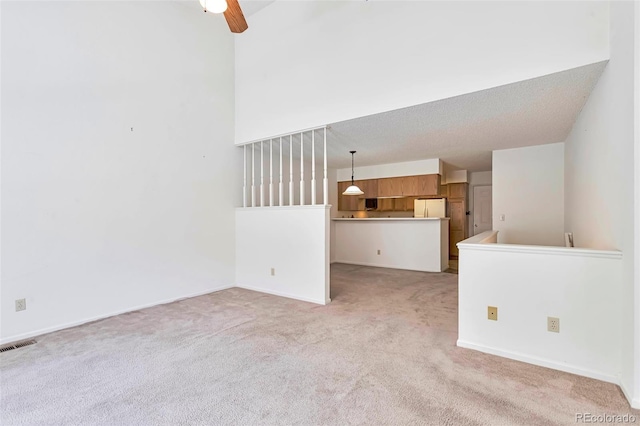 unfurnished living room featuring light carpet, ceiling fan, and baseboards