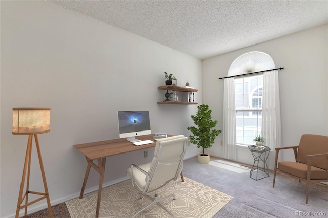 carpeted home office with a textured ceiling and baseboards