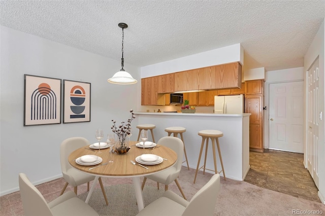 dining space featuring light carpet, a textured ceiling, and baseboards