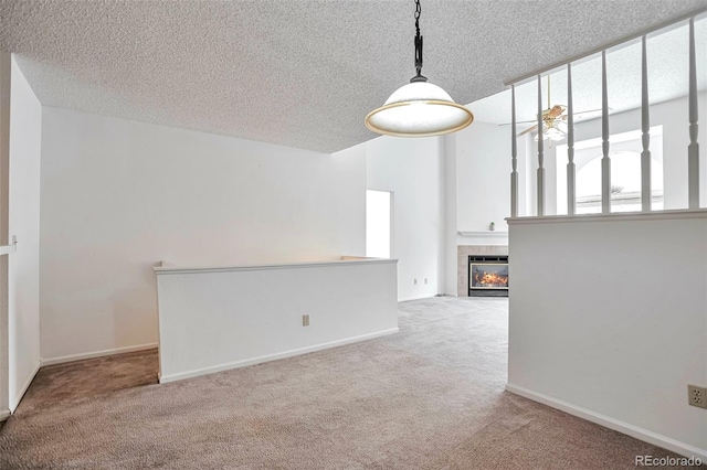 empty room featuring carpet floors, a textured ceiling, a tiled fireplace, and baseboards