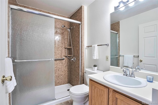bathroom with toilet, a stall shower, and vanity