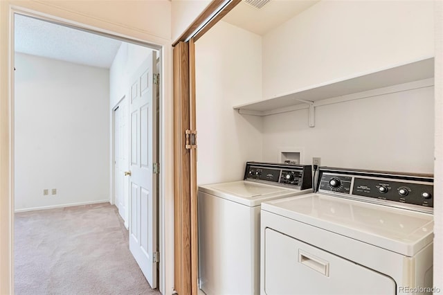 laundry room featuring washing machine and dryer, light carpet, and baseboards