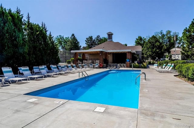 community pool with a patio area and fence