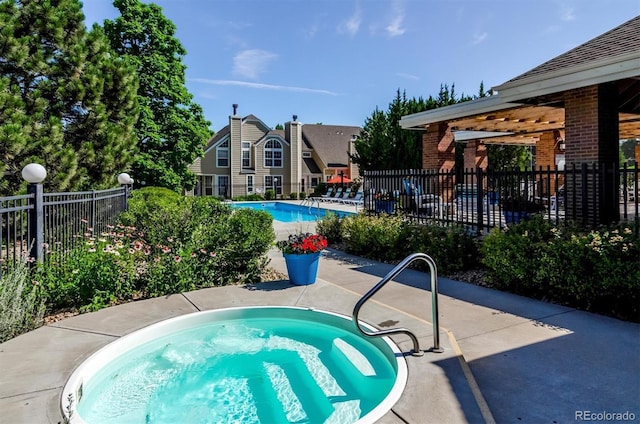 community pool with fence, a hot tub, and a patio area