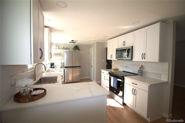 kitchen featuring tasteful backsplash, white cabinets, appliances with stainless steel finishes, light stone countertops, and a sink