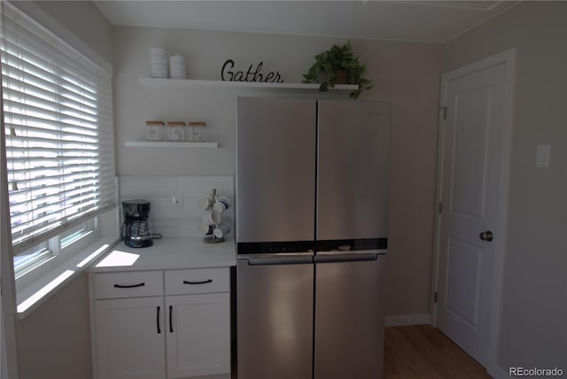 kitchen with light countertops, decorative backsplash, freestanding refrigerator, white cabinets, and wood finished floors