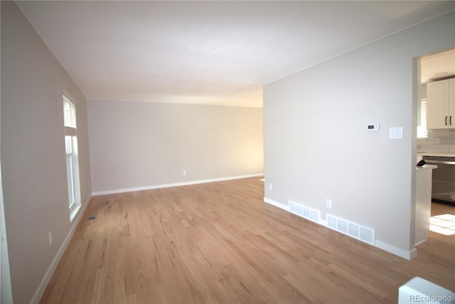 unfurnished room with light wood-type flooring, baseboards, and visible vents