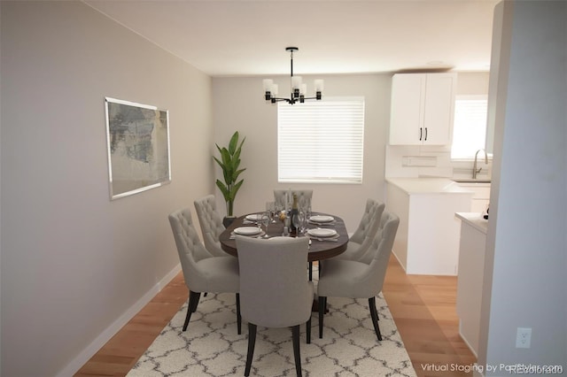 dining space with a notable chandelier, baseboards, and light wood-style floors