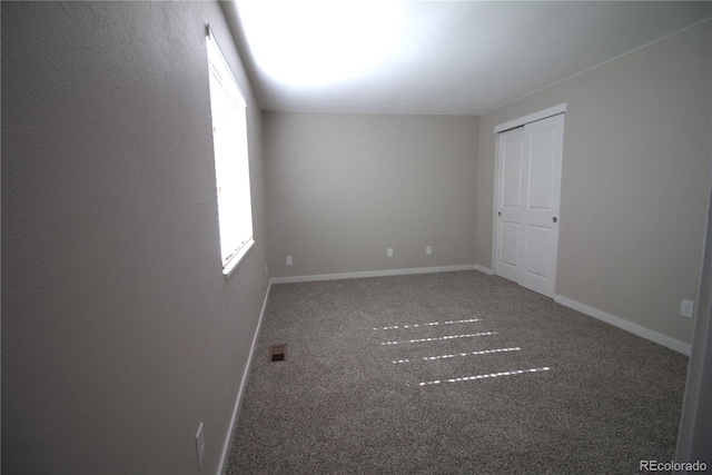 spare room featuring carpet floors, visible vents, and baseboards