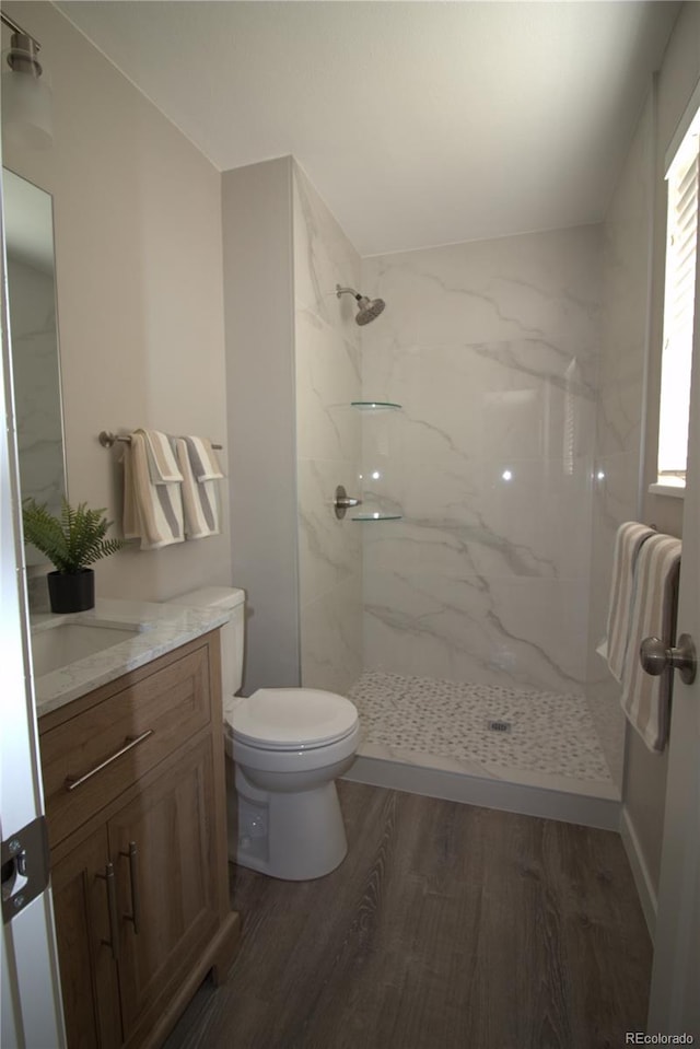 full bath with toilet, vanity, wood finished floors, and a marble finish shower