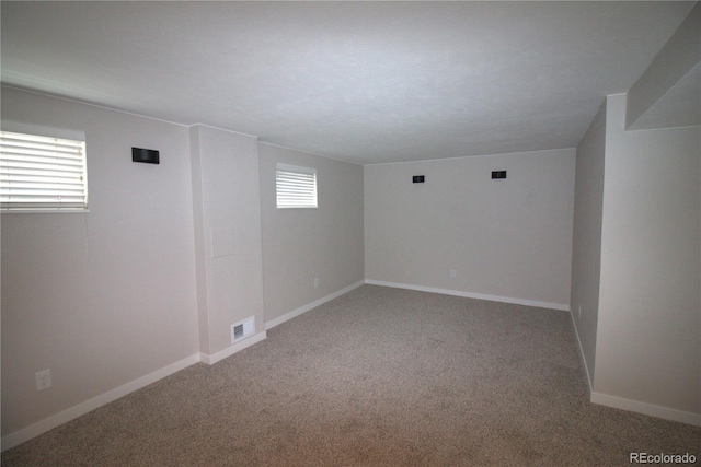 carpeted empty room featuring visible vents and baseboards