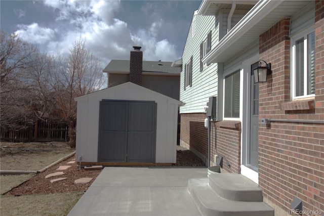 exterior space featuring an outbuilding, brick siding, fence, and a storage shed