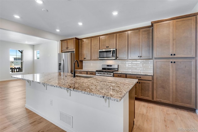 kitchen with a breakfast bar, visible vents, appliances with stainless steel finishes, light wood-style floors, and a sink