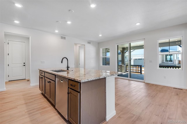 kitchen featuring light stone counters, light wood-style flooring, a sink, visible vents, and dishwasher