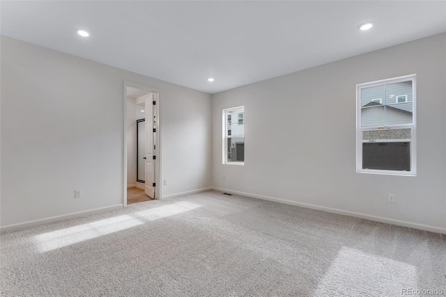 unfurnished room with light carpet, visible vents, baseboards, and recessed lighting