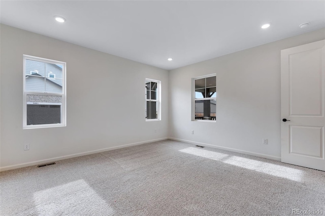 carpeted empty room featuring a wealth of natural light, visible vents, baseboards, and recessed lighting