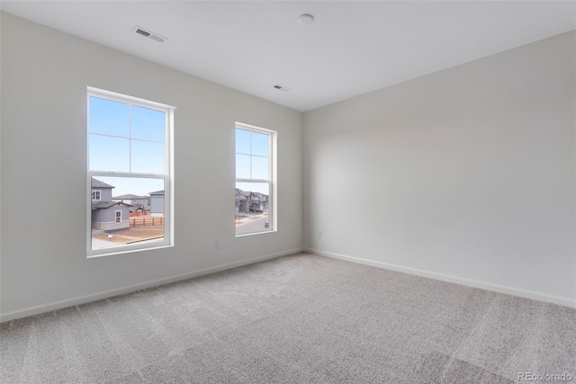 empty room featuring carpet floors, visible vents, and baseboards