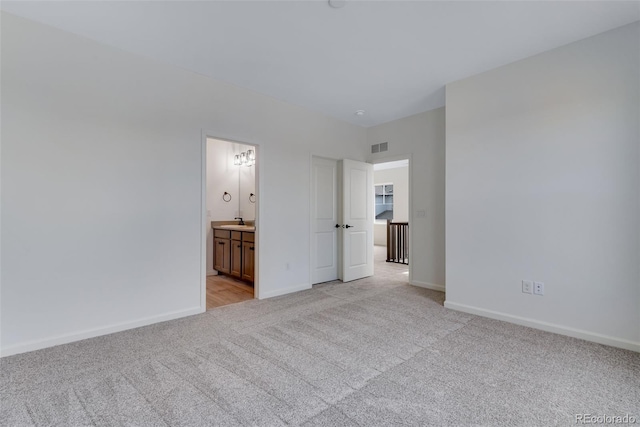 unfurnished bedroom with light carpet, visible vents, baseboards, and ensuite bathroom