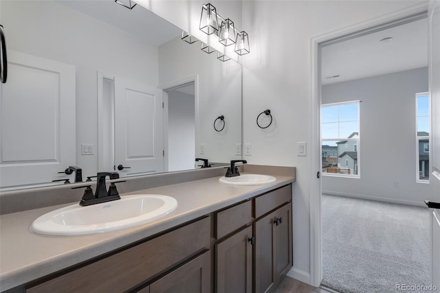 bathroom featuring a sink, baseboards, and double vanity