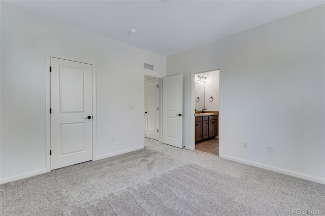 unfurnished bedroom featuring visible vents, light carpet, baseboards, and ensuite bathroom