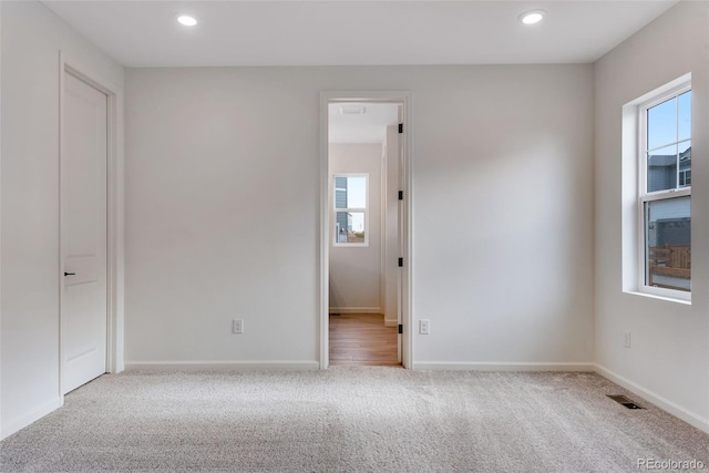 carpeted spare room featuring baseboards, visible vents, and recessed lighting