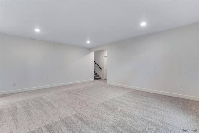 below grade area featuring light carpet, baseboards, stairway, and recessed lighting