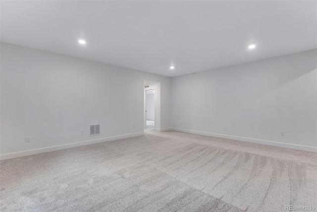 empty room featuring light colored carpet, visible vents, baseboards, and recessed lighting